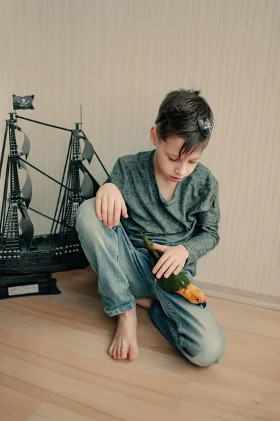 Boy pirate with a parrot and a sailboat — Stock Photo, Image