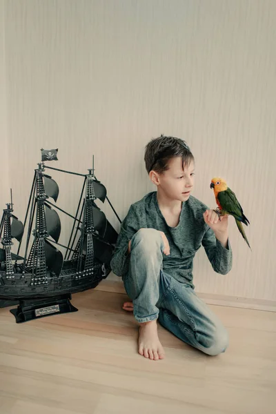 Хлопчик-пірат з папугою і вітрильним човном — стокове фото