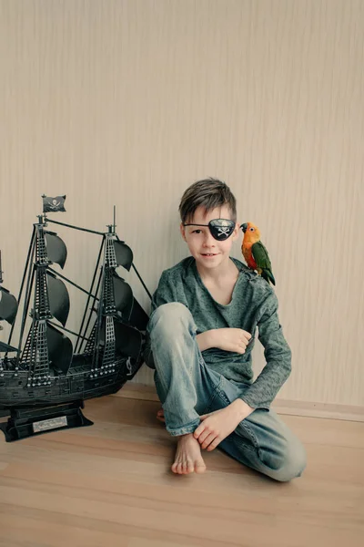 Boy pirate with a parrot and a sailboat — Stock Photo, Image