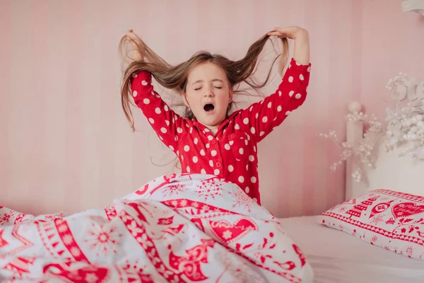 Flicka i röd pyjamas sover i sängen — Stockfoto