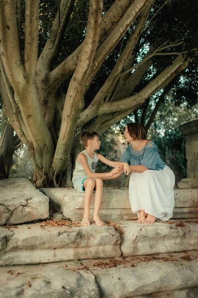 Mor med liten pojke i parken under ett träd — Stockfoto