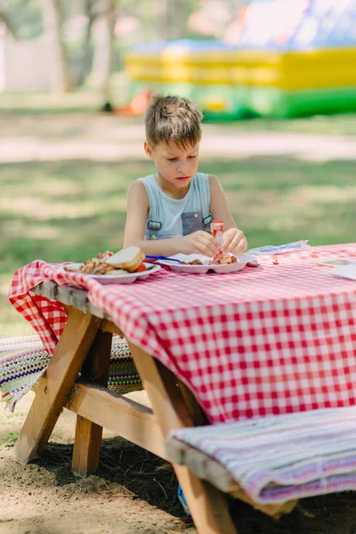 Boy eats in a summer park — Stock Photo, Image