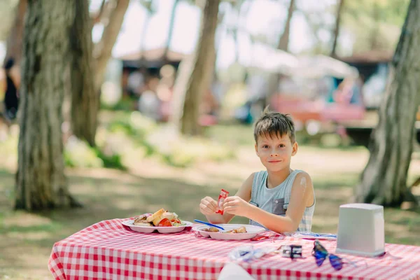 Pojken äter i en sommar park — Stockfoto