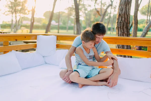 Filho com seu pai em um sofá de madeira — Fotografia de Stock