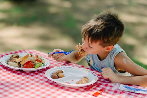 लड़का एक ग्रीष्मकालीन पार्क में खाता है — स्टॉक फ़ोटो, इमेज