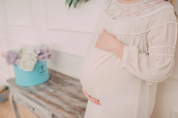 Vientre de una mujer embarazada y flores — Foto de Stock