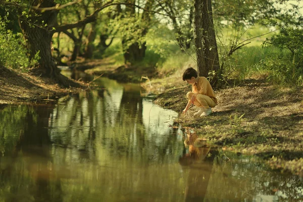 V lese nedaleko řeky roztomilý chlapec — Stock fotografie