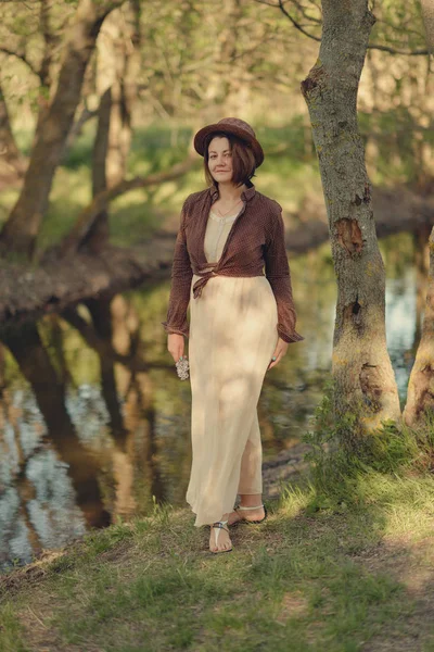 Vrouw in hoed in bossen door de rivier — Stockfoto