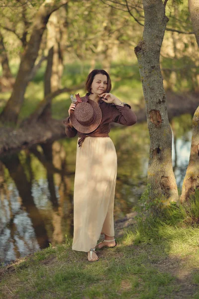 Mujer en sombrero en el bosque junto al río — Foto de Stock