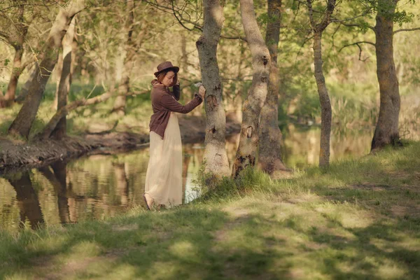 Mujer en sombrero en el bosque junto al río — Foto de Stock