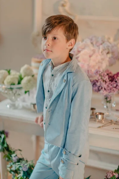 Der kleine Junge im blauen Anzug im Atelier mit Blumen — Stockfoto