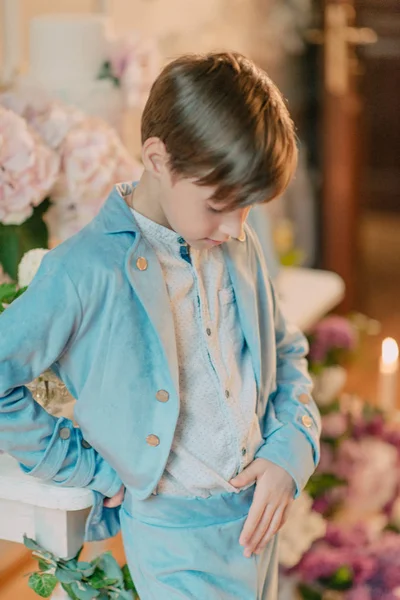 Het kleine jongetje in het blauwe pak in de Studio met bloemen — Stockfoto