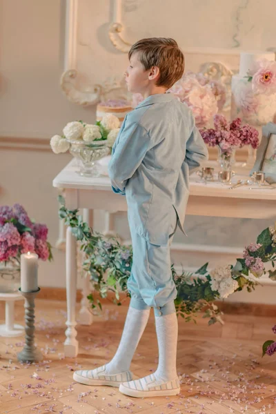 Het kleine jongetje in het blauwe pak in de Studio met bloemen — Stockfoto