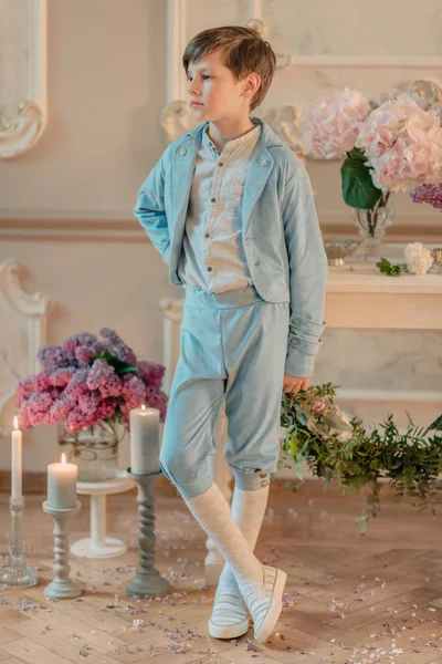 Chlapeček v modrém obleku v ateliéru s květinami — Stock fotografie