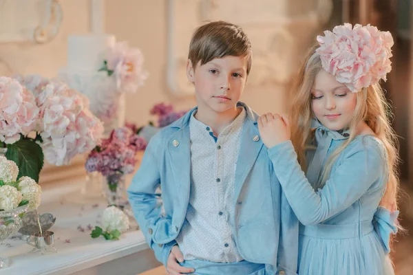 Kleine jongen en meisje in de blauwe jurk in de Studio met bloemen — Stockfoto