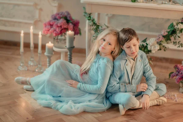 小男孩和女孩在蓝色的连衣裙在演播室与花 — 图库照片