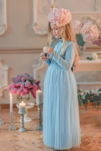 Blond meisje in blauwe jurk en met een bloem op het hoofd — Stockfoto