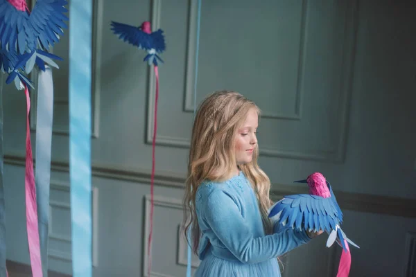 Blond meisje in blauwe jurk met vogels — Stockfoto