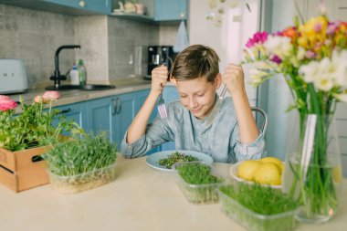 Mutfakta mikroyeşil tişörtlü bir çocuk.