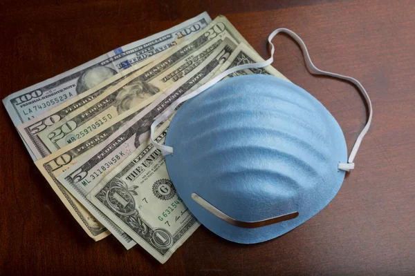 Mavi tıbbi koruyucu yüz maskesi ve para. Yüz maskesi kirliliğe, virüse, gribe karşı koruma. Sağlık ve finans konsepti. Sağlık hizmetlerinin maliyeti