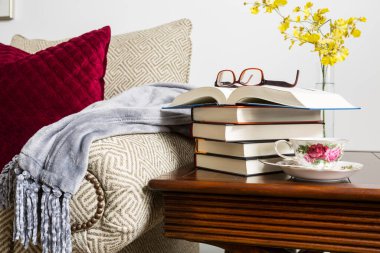 Ev kavramı, evde kitap, bardak ve dinlendirici bir öğleden sonra masadaki bir fincan kahveyle okumak.