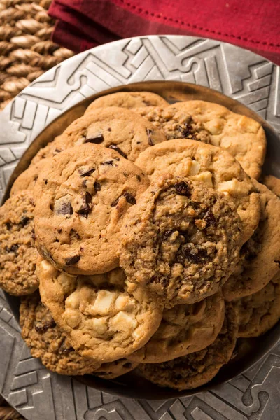 Çeşitli aromalı kurabiyelerden oluşan bir gruba yakın çekim. Çikolata parçacıklı, macadamia fındıklı, yulaf ezmeli kuru üzümlü, yemekten sonra servis edilen kahve fincanlarıyla gümüş bir tabakta veya atıştırmalık olarak.