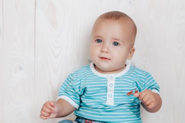 Çocuk gizemli bir şekilde hafif bir arka plan üzerinde gülümseyerek kameraya benziyor.