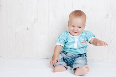 Hafif bir arka plan üzerinde gülümseyen katta oturan çocuk