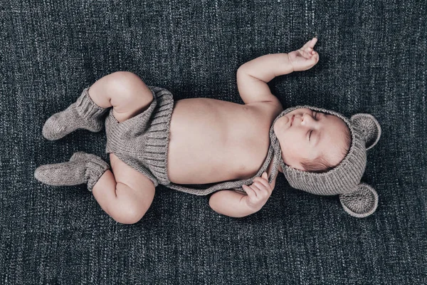 Bebé recién nacido en un traje de punto dormido en un cuadros grises — Foto de Stock