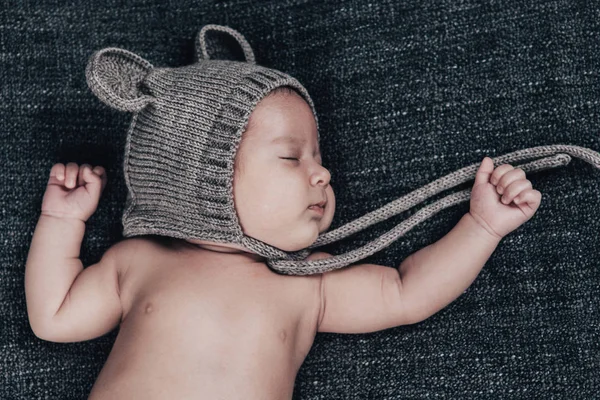 Un bebé recién nacido con una gorra duerme sobre un cuadros grises — Foto de Stock