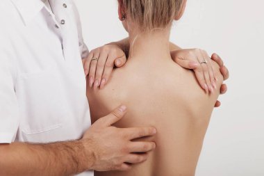 Osteopat bir kıza sırt ve omuz masajı yapar.