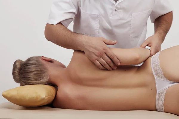 Osteopat bir kıza sırt ve omuz masajı yapar.