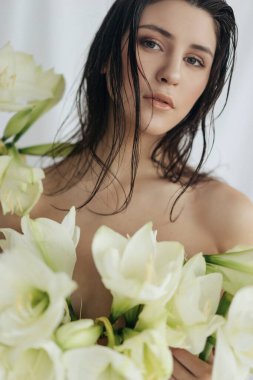 Beyaz arkaplanda beyaz güller ve amil çiçekleri olan bir kız.