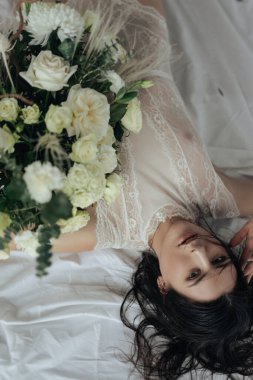 Beyaz arkaplanda beyaz güller ve amil çiçekleri olan bir kız.