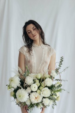 Beyaz arkaplanda beyaz güller ve amil çiçekleri olan bir kız.