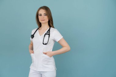 Boynunda steteskop olan doktor kadın mavi arka planda görünüyor.