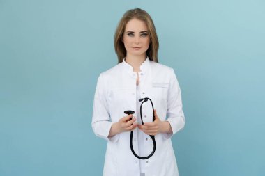 Elinde steteskop olan pozitif kadın doktor mavi arka planda.