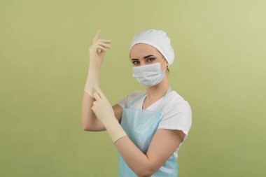 Tıbbi önlüklü doktor ve yeşil arka planlı eldivenler.