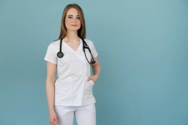 Boynunda steteskop olan doktor kadın mavi arka planda görünüyor.