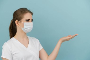 Maskeli kadın doktor mavi arkaplandaki öğe veya listeye işaret ediyor