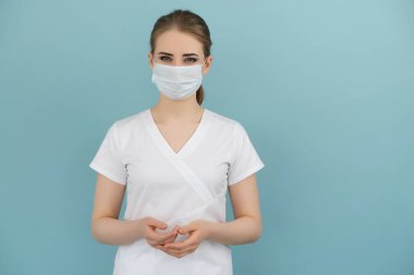 Maskeli kadın doktor mavi bir arka planda endişe ve korku gösteriyor.