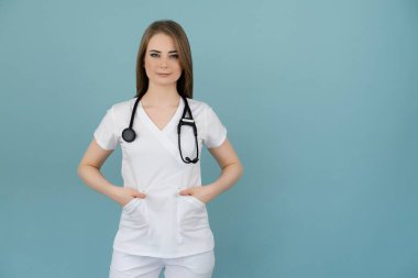 Boynunda steteskop olan doktor kadın mavi arka planda görünüyor.