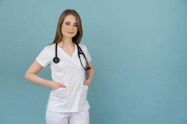 Boynunda steteskop olan doktor kadın mavi arka planda görünüyor.