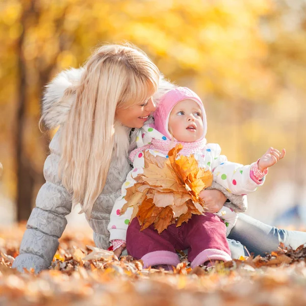 Mor och dotter promenader i parken hösten. Skönhet naturen scen med färgglada lövverk bakgrund, gula träd och blad på höstsäsongen. Hösten utomhus livsstil. Lyckligt leende familjen koppla av på hösten blad — Stockfoto