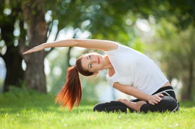 Yoga dışarıda. Yoga egzersizleri yapan, parkta meditasyon yapan mutlu bir kadın. Yoga meditasyonu. Sağlıklı yaşam tarzı ve rahatlama kavramı. Çimenlerde yoga yapan güzel bir kadın.