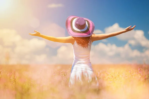 Счастливая женщина наслаждается жизнью в поле с цветами. Красота природы, голубое облачное небо и красочное поле с цветами. Наружный образ жизни. Понятие свободы. Женщина в летнем поле — стоковое фото