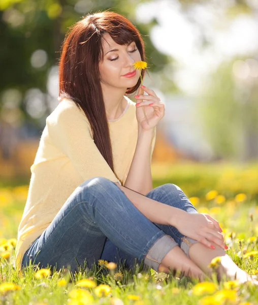 Cute woman rest in the park with dandelions. Happy woman relax in flowers at sunny day. Free woman enjoying the nature. Beautiful girl outdoor. Enjoyment and happiness — Stock Photo, Image