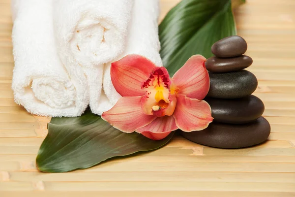 Spa background. White towels on exotic plant, beautiful orchid flower and balancing stones for relax spa massage and body treatment. Asian medicine with aroma and stone therapy for beauty healthy body — Stock Photo, Image