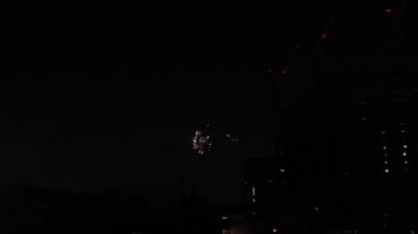 Yaz gecesi Tokyo 'daki şehir merkezindeki binanın yanında havai fişekler.