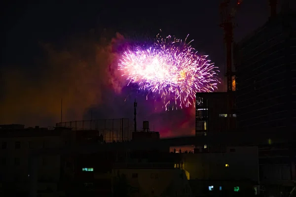 Фейерверки возле здания в городе Токио в летнюю ночь — стоковое фото